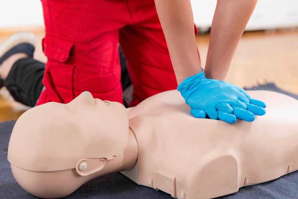 formateur qui fait un massage cardiaque à un mannequin lors d'une formation aux gestes de premiers secours